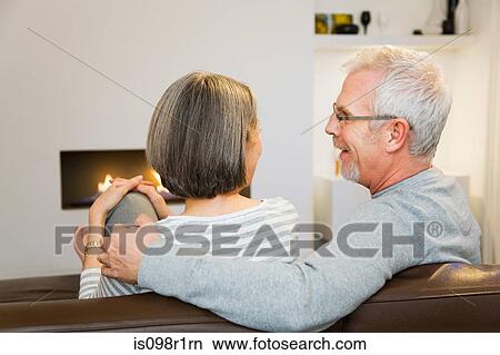 Picture - Mature couple sat next to the fire. Fotosearch