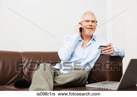 Stock Photograph - Mature man using telephone banking. Fotosearch