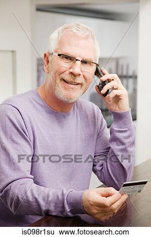 Stock Photograph - Mature man using telephone banking. Fotosearch