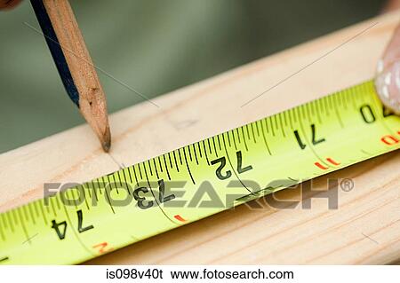Stock Photograph - Measuring plank of wood and marking with pencil. Fotosearch