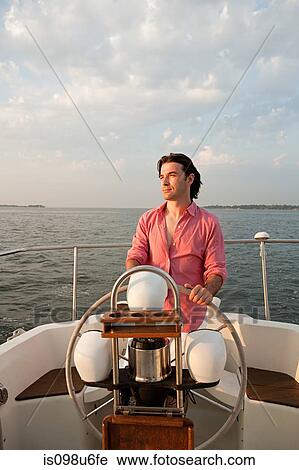Mid adult man steering yacht View Large Photo Image Stock Image - Mid adult man steering yacht. Fotosearch