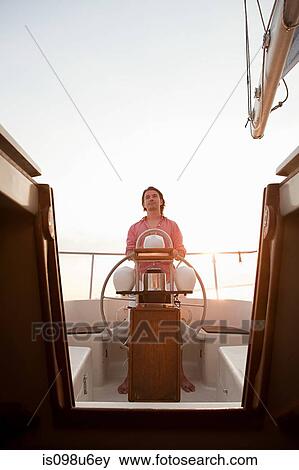 Stock Photo - Mid adult man steering yacht. Fotosearch