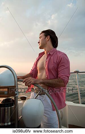Mid adult man steering yacht View Large Photo Image Stock Photo - Mid adult man steering yacht. Fotosearch