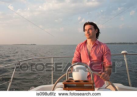 Mid adult man steering yacht View Large Photo Image Stock Photo - Mid adult man steering yacht. Fotosearch