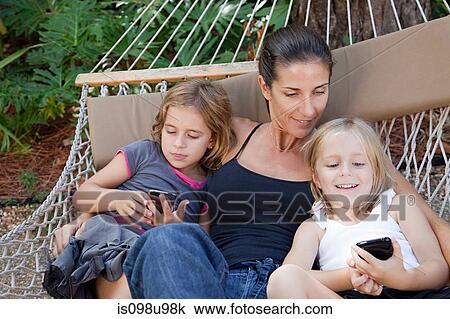 Mother and daughters on hammock with smartphones View Large Photo Image Stock Image - Mother and daughters on hammock with smartphones. Fotosearch