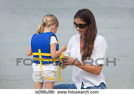 Stock Photography - Mother putting life jacket on daughter. Fotosearch