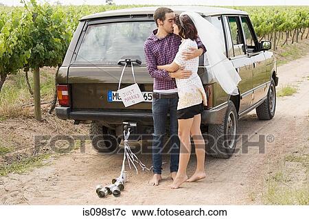 Newlywed couple kissing by vehicle View Large Photo Image Stock Image - Newlywed couple kissing by vehicle. Fotosearch