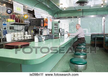 Stock Image - Old man sitting in a diner. Fotosearch