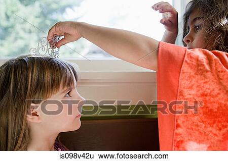 One girl putting tiara on another girl View Large Photo Image Stock Photograph - One girl putting tiara on another girl. Fotosearch