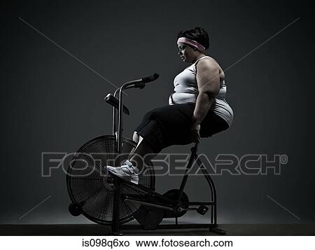 Overweight woman on exercise bike View Large Photo Image Picture - Overweight woman on exercise bike. Fotosearch
