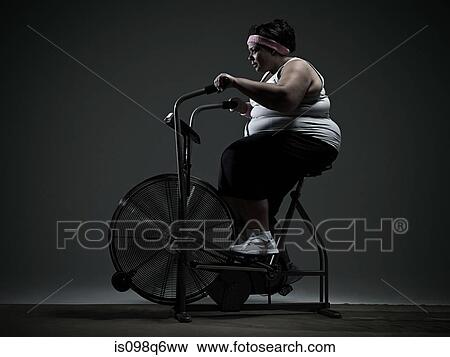 Overweight woman on exercise bike View Large Photo Image Stock Photo - Overweight woman on exercise bike. Fotosearch