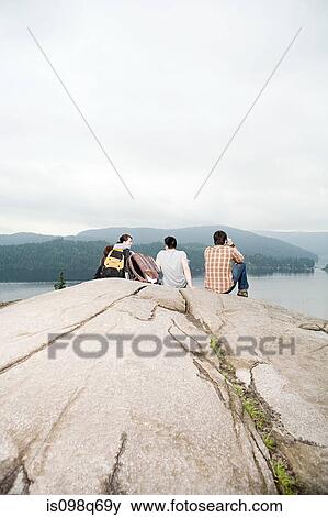 Stock Photo - People on rock by a lake. Fotosearch