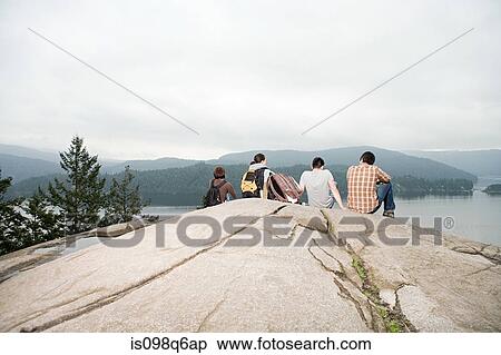 Stock Photography - People on rock by a lake. Fotosearch