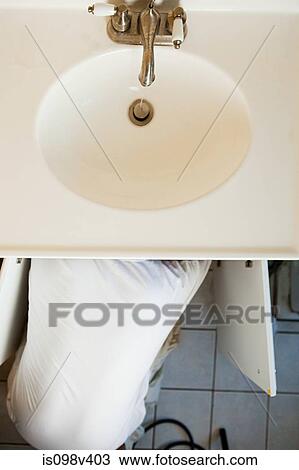 Stock Image - Plumber repairing sink. Fotosearch