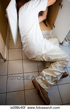 Stock Image - Plumber repairing sink. Fotosearch