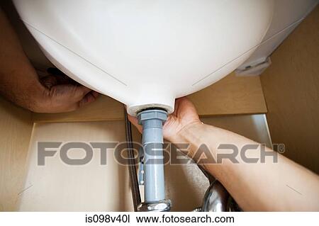 Stock Image - Plumber repairing sink. Fotosearch