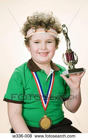 Stock Photo - Portrait of a boy holding a trophy. Fotosearch