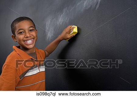 Stock Image - Portrait of a boy wiping a blackboard. Fotosearch