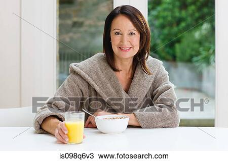 Stock Image - Portrait of a mature woman having breakfast. Fotosearch