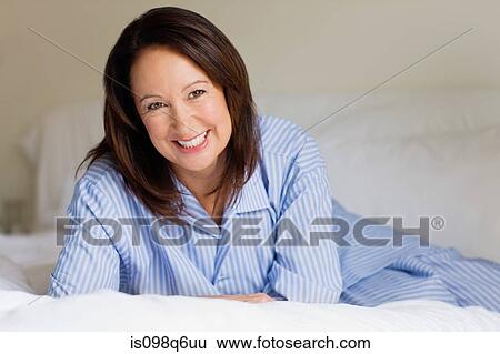 Portrait of a mature woman lying on a bed View Large Photo Image Stock Photograph - Portrait of a mature woman lying on a bed. Fotosearch