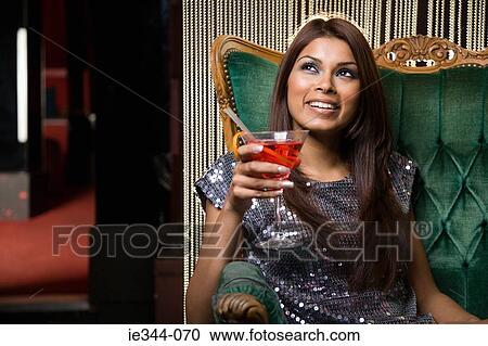 Portrait of a young woman holding a cocktail View Large Photo Image Stock Image - Portrait of a young woman holding a cocktail. Fotosearch
