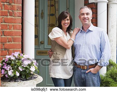 Stock Image - Portrait of man and woman at their front door. Fotosearch