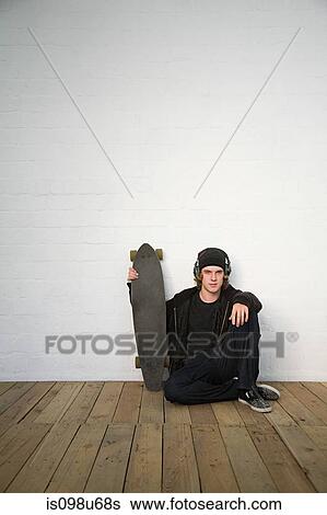 Portrait of teenage boy sitting on floor with skateboard View Large Photo Image Stock Photograph - Portrait of teenage boy sitting on floor with skateboard. Fotosearch