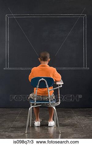 Rear view of a boy sat at a desk View Large Photo Image Stock Image - Rear view of a boy sat at a desk. Fotosearch