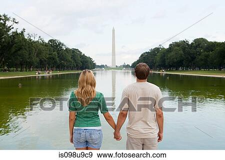 Stock Photo - Rear view of young couple looking towards washington monument. Fotosearch