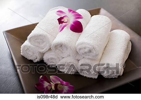 Stock Image - Rolled towels and orchid flowers. Fotosearch