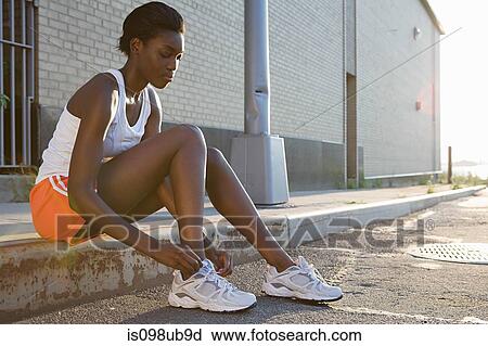 Stock Image - Runner sitting on sidewalk. Fotosearch