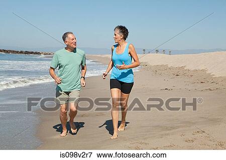 Stock Photo - Senior couple jogging on beach. Fotosearch