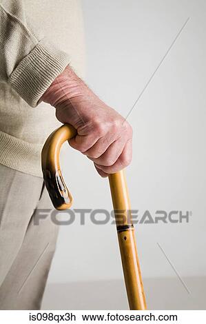 Stock Image - Senior man holding walking stick. Fotosearch
