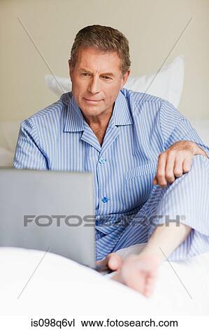 Senior man using a laptop in bed View Large Photo Image Stock Image - Senior man using a laptop in bed. Fotosearch