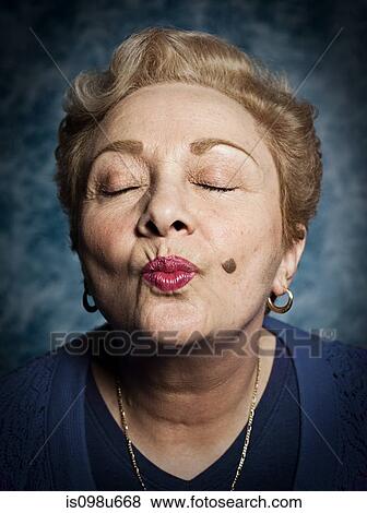 Senior woman blowing kiss, eyes closed View Large Photo Image Stock Photo - Senior woman blowing kiss, eyes closed. Fotosearch