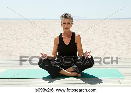 Stock Photograph - Senior woman doing yoga on beach. Fotosearch