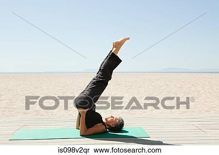 Stock Photography - Senior woman doing yoga on beach. Fotosearch