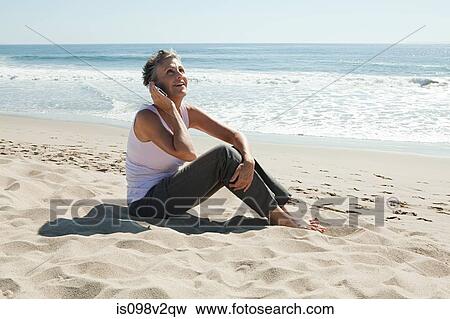 Stock Photo - Senior woman using cell phone on beach. Fotosearch