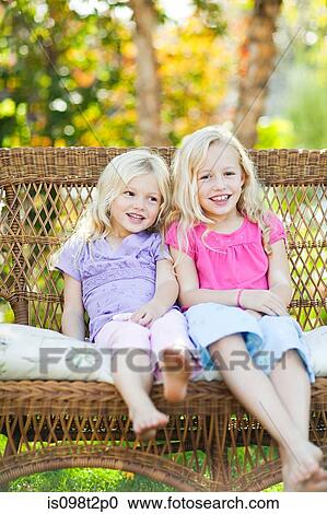 Sisters sitting on seat in garden View Large Photo Image Stock Image - Sisters sitting on seat in garden. Fotosearch