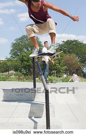Skateboarder jumping over railing View Large Photo Image Stock Image - Skateboarder jumping over railing. Fotosearch