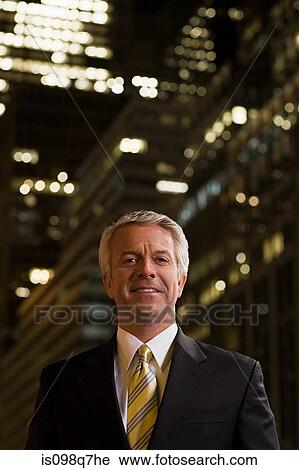 Stock Image - Smiling businessman at night. Fotosearch