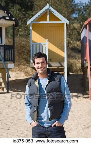 Smiling man standing near beach huts View Large Photo Image Stock Image - Smiling man standing near beach huts. Fotosearch