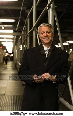 Stock Photo - Smiling mature businessman text messaging. Fotosearch