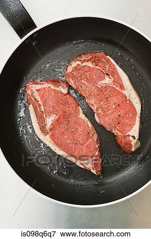 Stock Photo - Steaks in a frying pan. Fotosearch