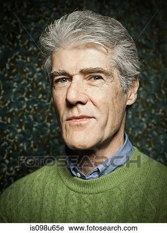 Stock Image - Studio portrait of senior man wearing green sweater. Fotosearch
