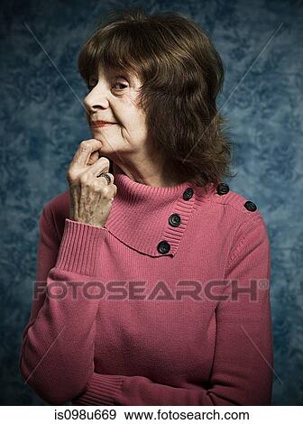 Stock Photo - Suspicious senior woman with hand on chin. Fotosearch