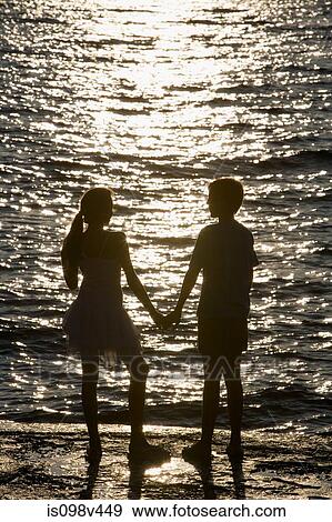 Teenage couple watching sunset over sea View Large Photo Image Stock Photo - Teenage couple watching sunset over sea. Fotosearch