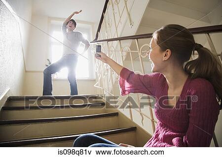Stock Photo - Teenage girl photographing young man on cell phone. Fotosearch