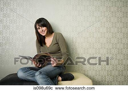 Stock Image - Teenage girl reading magazine. Fotosearch