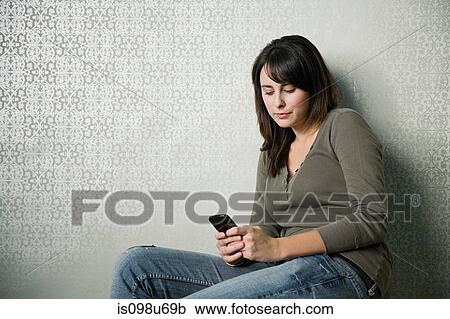 Stock Image - Teenage girl texting on smartphone. Fotosearch